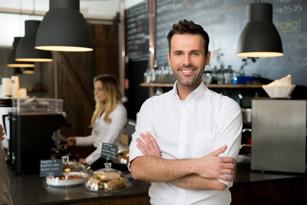 Man standing with his arms crossed in a coffee shop